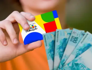 Cartão do Bolsa Família sendo segurado na mão com notas de dinheiro ao lado, representando o pagamento do benefício social.