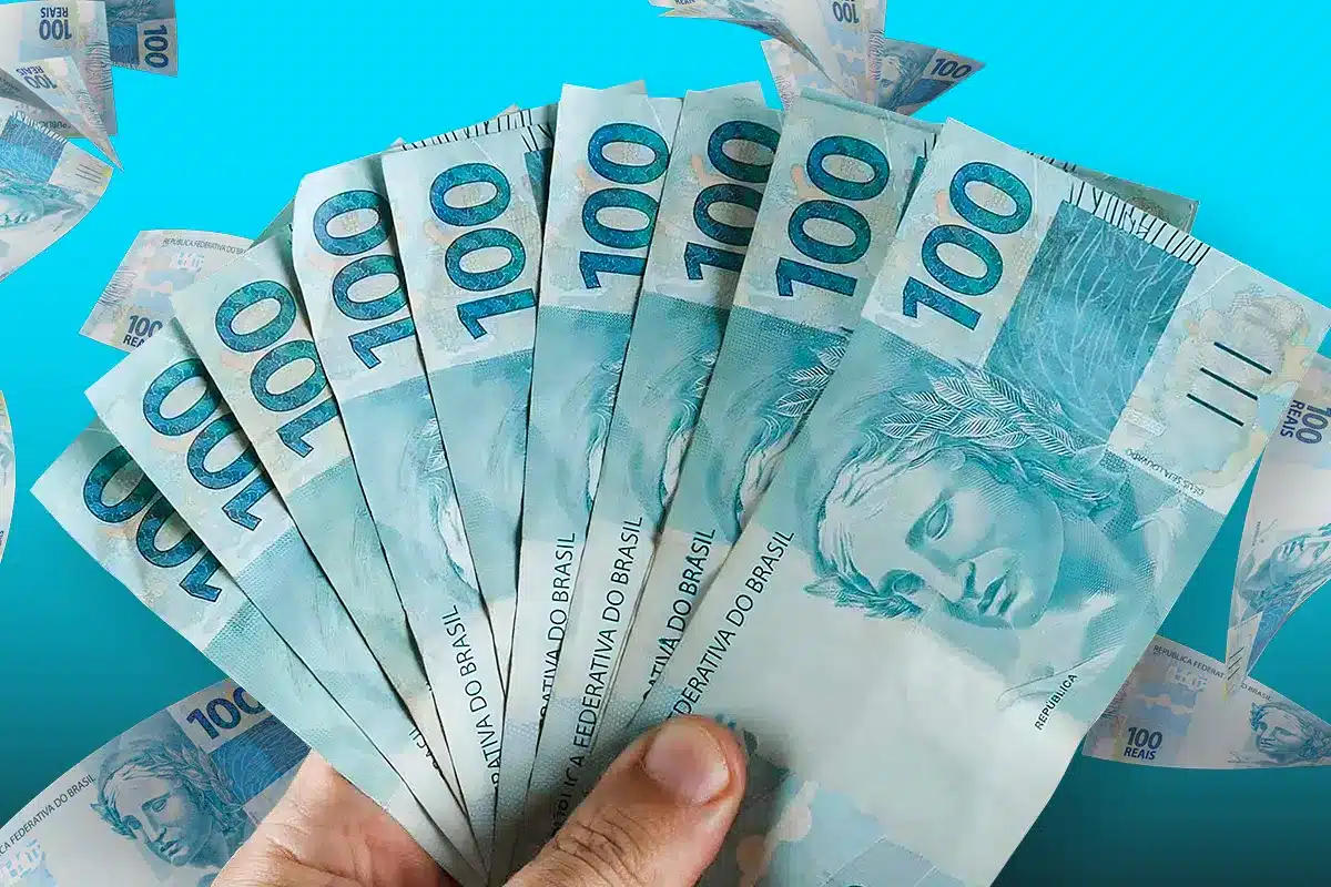 Pessoa segurando várias notas de cem reais abertas em leque